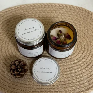 Detailed view of scented candle in brown glass jar with dried rose buds and metal lid.