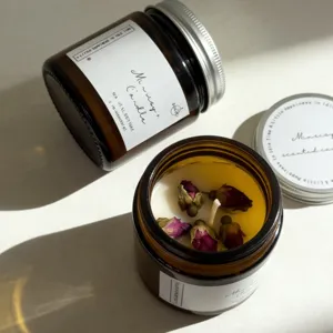 Closeup detail of scented candle in amber glass jar with natural soy wax and dried rose petals.