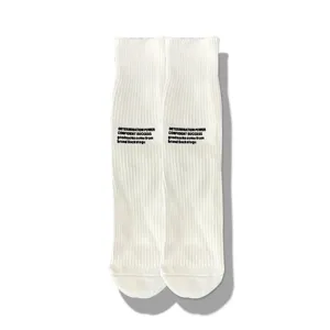 Detail shot of white ribbed mid-calf socks featuring black letter print and casual streetwear style.