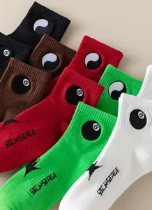 Primo piano dettagliato di calze da skate in cotone colorato con ricami 8-ball e motivi yin-yang.