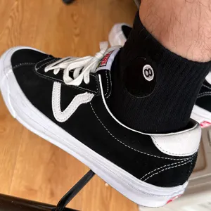 Scarpe da skate nere abbinate a classici calzini in cotone con ricamo della palla 8 per lo sport.