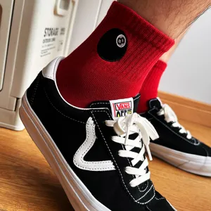 Dettaglio in primo piano di calzini da skate rossi con ricamo elegante della palla otto nera.