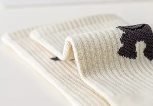 Close-up detail of beige knit fashion socks featuring a cute dancing bear pattern, stylish streetwear.