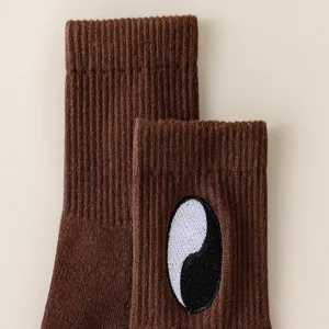 Calzini a coste marroni con classico motivo ricamato yin yang. Comodi ed eleganti.