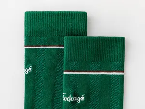 Primer plano detallado de calcetines deportivos de malla verde con rayas blancas marrones y elástico.