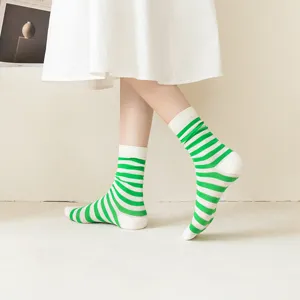 Close-up detail of green and white striped mesh mid-calf socks worn in a clean lifestyle setting.