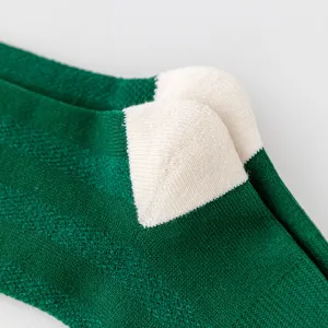 Primer plano detallado de calcetines de compresión deportivos de malla verde y blanca.