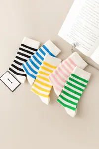 Close-up detail of colorful striped mid-tube socks arranged neatly on a beige table surface.