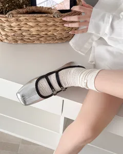 Detailaufnahme von weißen Damen-Netz-Spitzensocken kombiniert mit silbernen Mary-Jane-Schuhen.