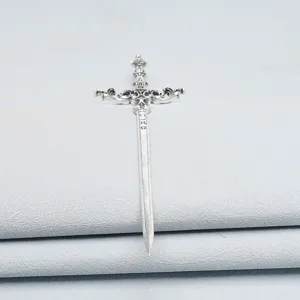 Close-up of a vintage cross sword metal hair stick, silver finish with carved details.