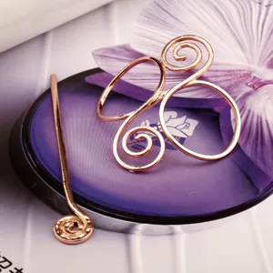 Detailed shot of rose gold vintage metal hair pin with unique Celtic spiral design, close-up.