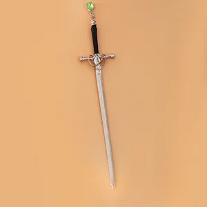 Close-up van vintage metalen zwaard haarstick met groene edelsteen hanger en zwart handvat.