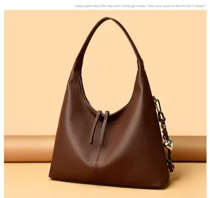 Brown leather hobo shoulder bag detail, elegant slouchy design with zipper and metal charm.