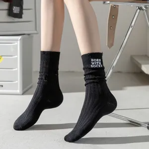 Close-up of black distressed ribbed crew socks with white BORN WITH SOCKS embroidery design.