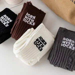 Close-up of distressed knit socks with embroidery text detail, casual style winter wear.