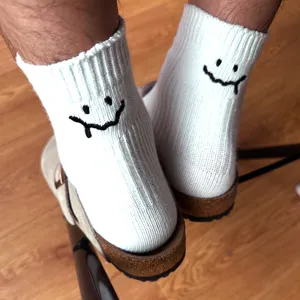 Comfortable white cotton socks featuring trendy embroidered melted smiley face design for daily wear.