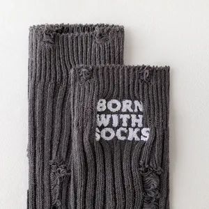 Close-up detail of dark grey distressed knit socks with white embroidered lettering design.