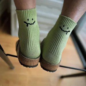 Close-up detail of light green cotton crew socks with embroidered melting smile for casual wear.