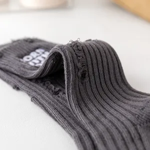 Detailed shot of dark grey ribbed distressed knit calf socks, showcasing unique grunge style texture.