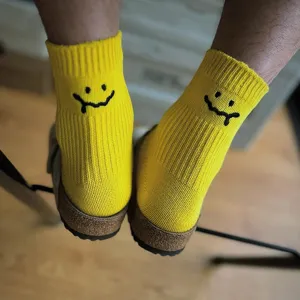 Bright yellow cotton socks with black melting smile embroidery, casual streetwear style.