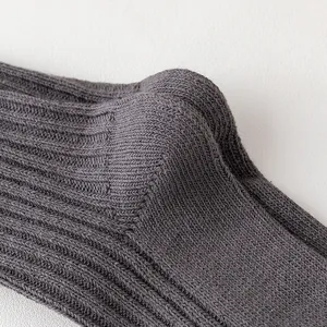 Close-up detail of dark grey ribbed knit socks, showing thick needle texture and quality.