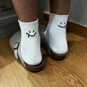 Detail view of white cotton short socks with embroidered melting smiley face, casual daily wear.