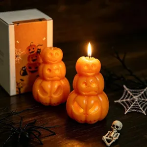 Gros plan détaillé de bougies parfumées citrouilles empilées aux visages effrayants pour ambiance Halloween.