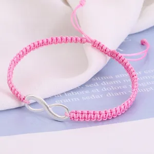 Close-up of handmade pink braided friendship bracelet with silver infinity symbol.
