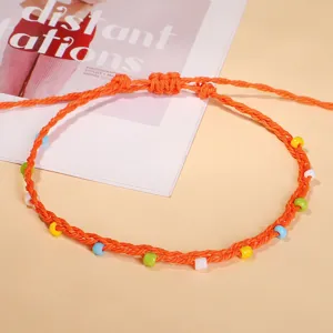 Detailed macro view of a handmade bohemian anklet with colorful beads on orange wax cord