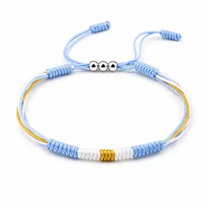 Detailed macro shot of light blue white and gold woven bracelet with silver beads