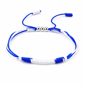 Detailed view of handmade blue and white braided friendship bracelet with metal beads