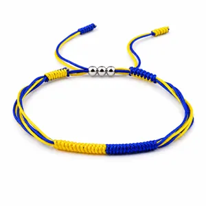 Detail view of handmade yellow and blue braided bracelet with three silver copper beads.