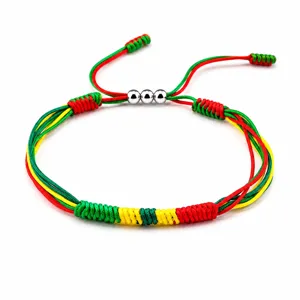 Close-up view of a red, yellow, and green woven friendship bracelet with copper beads