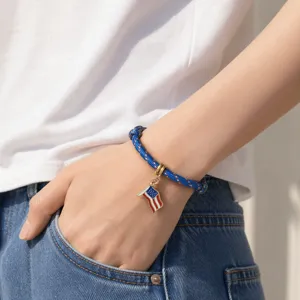 Detailaufnahme eines Armbands mit USA-Flaggen-Anhänger aus blauem Paracord am Handgelenk