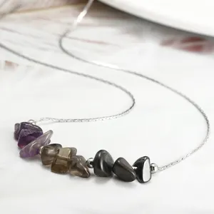 Close-up of handmade necklace featuring raw amethyst and smoky quartz stones