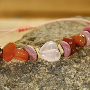 Dettaglio di quarzo rosa a forma di cuore e perline di agata rossa su bracciale intrecciato