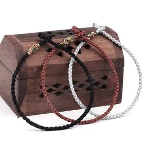 Detailed view of three handmade woven rope bracelets in various colors on a vintage wooden box