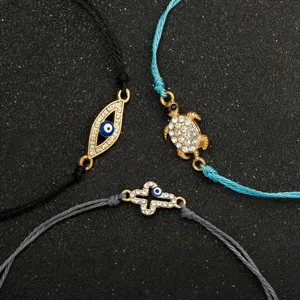 Dettaglio di tre braccialetti bohémien in corda cerata con ciondoli a forma di occhio e tartaruga.