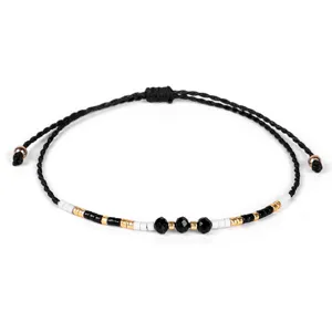 Dettaglio di un bracciale intrecciato a mano con perline nere, bianche e oro