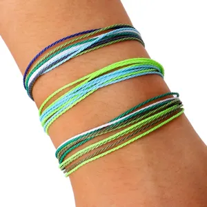 Primer plano de tres juegos de pulseras ajustables trenzadas con cordón de cera de colores en la muñeca