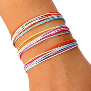 Primer plano de un juego de tres pulseras de playa de cordón de cera trenzado de colores.
