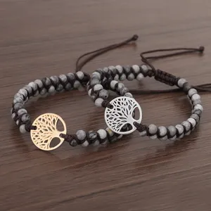 Détail de bracelets tressés en pierre de carte avec des breloques arbre de vie dorées