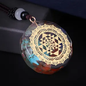 Primer plano del colgante Orgone Yoga con Sri Yantra dorado y cristales curativos.
