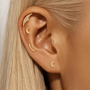 Detailed macro view of gold plated crescent moon ear bone studs with micro-pave stones