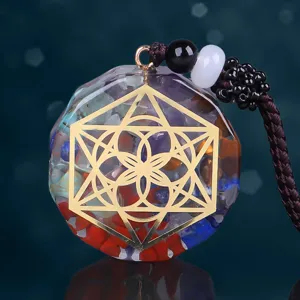 Detalle de un colgante hexagonal de resina con piedras naturales y un símbolo dorado yoga