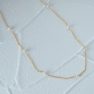 Macro detail of a 925 sterling silver gold-plated necklace with elegant white pearls.