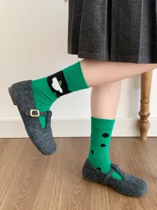 Primo piano di calzini verdi asimmetrici con orsetto simpatico e pois neri dettagliati.