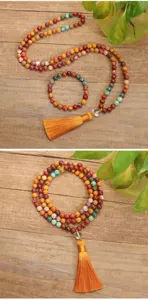 Macro dettaglio della collana Yoga Mala con 108 pietre e lunga nappa di seta gialla.