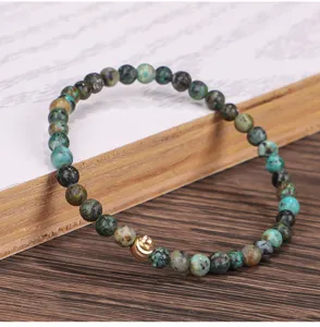 Detailaufnahme eines elastischen Armbands aus afrikanischem Türkis mit goldener Perle.