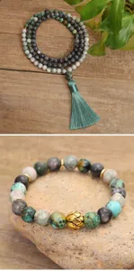 Detail view of African turquoise mala beads with tassel and golden lotus charm bracelet.